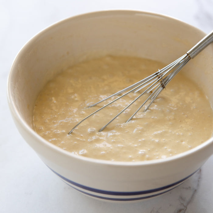 Einkorn sourdough pancake batter being whisked in a ceramic bowl
