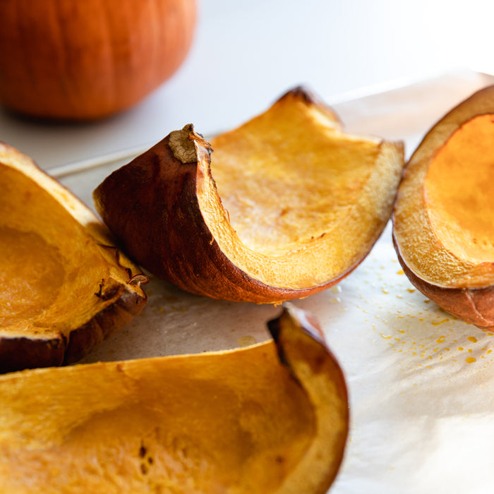 Roasted pumpkin halves cooling on a parchment-lined baking sheet
