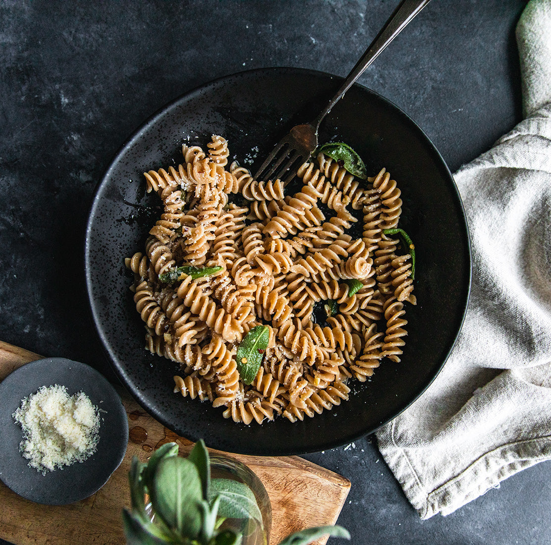 Cooked organic whole wheat fusilli tossed with garlic and olive oil in a black skillet, garnished with parsley
