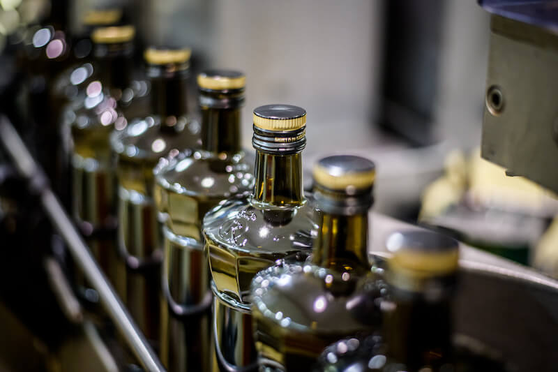 Olive oil bottles moving along a conveyor on a bottling line in a production facility