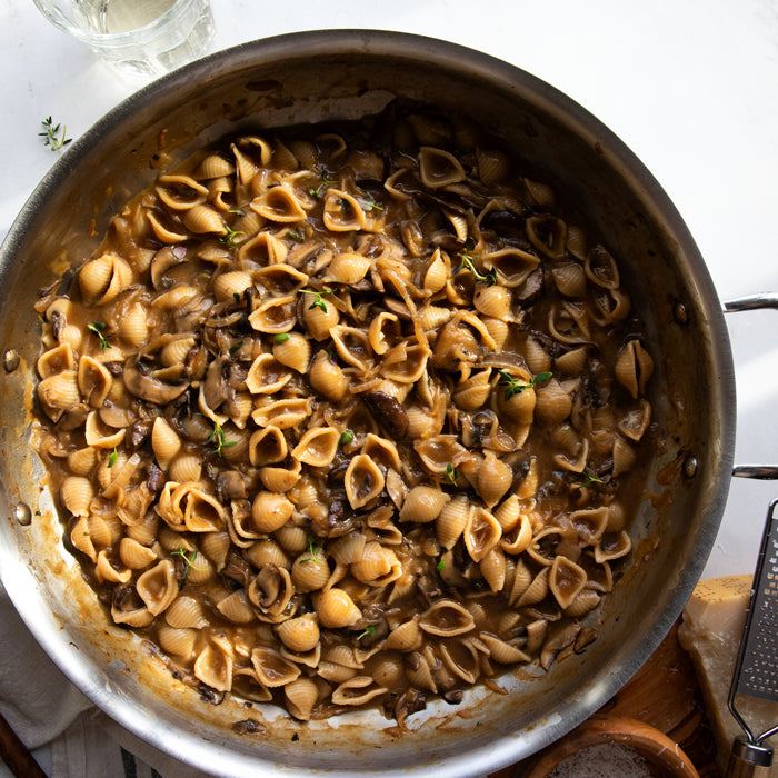 One-pan French onion pasta with mushrooms in a skillet, shell pasta in caramelized onion sauce with thyme