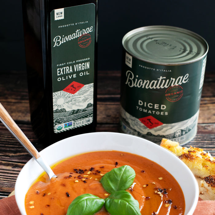 Rustic tomato soup with basil garnish and toasted bread, Bionaturae olive oil bottle and diced tomatoes can in background