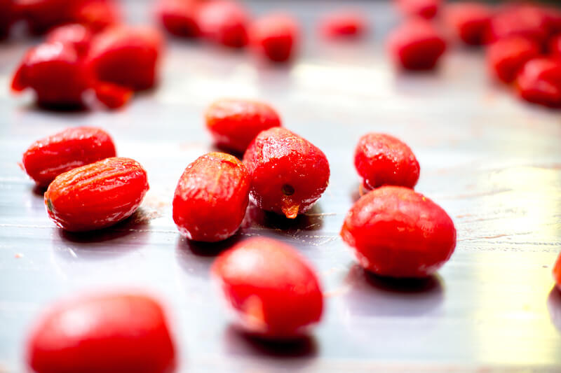 Close-up of peeled organic plum tomatoes on a stainless steel production tray