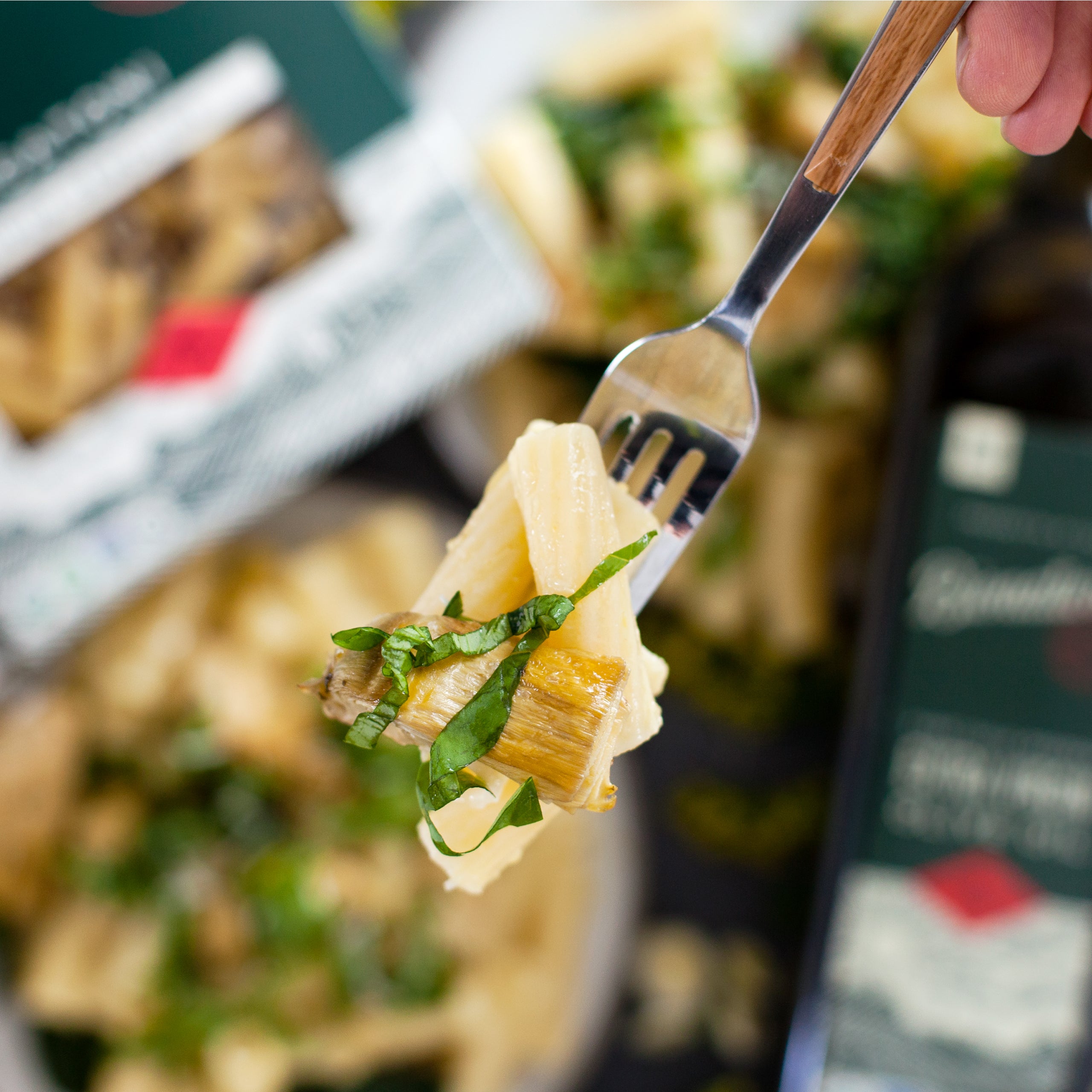 Cooked organic rigatoni twirled on a fork with parsley garnish, blurred plate and product box in the background