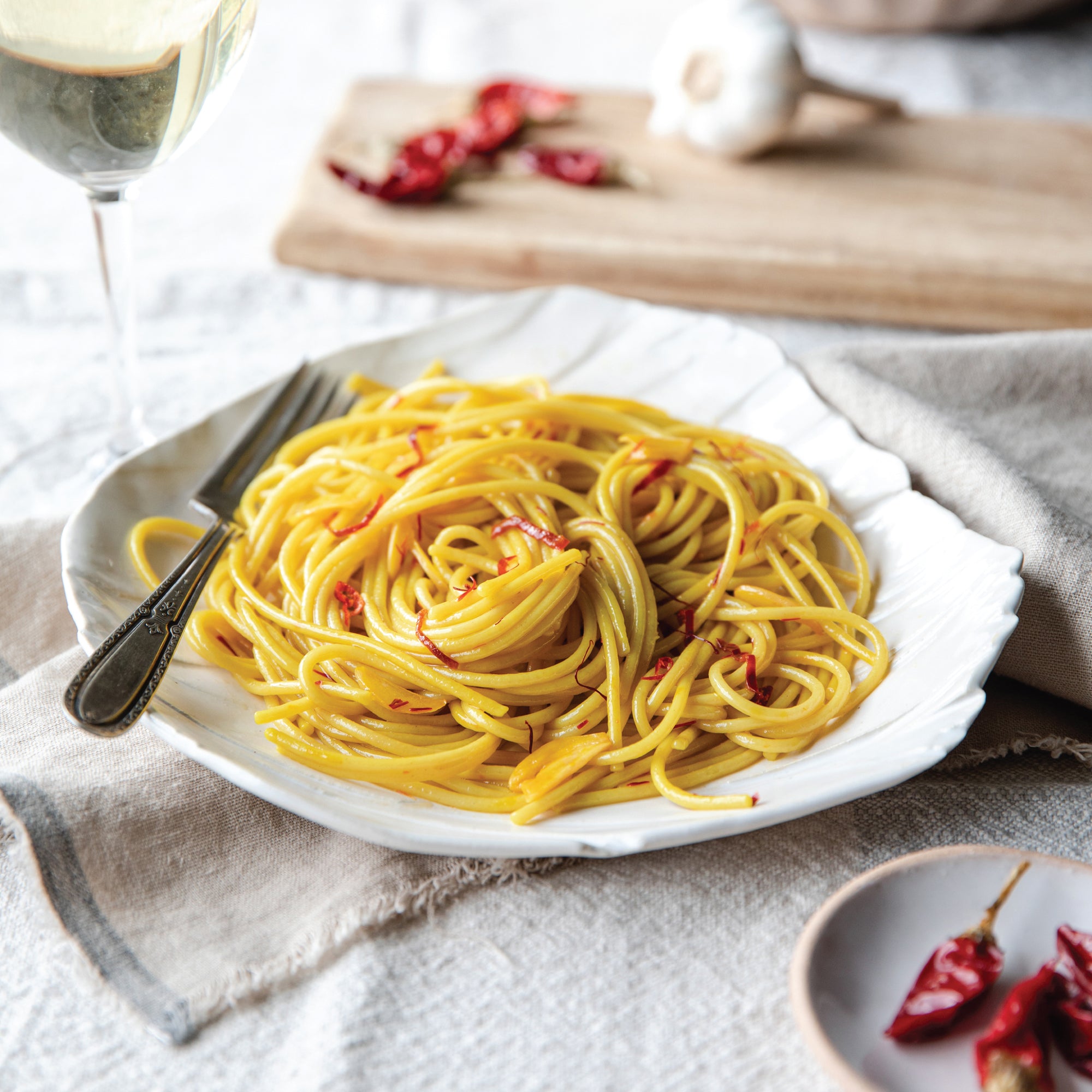 Cooked organic gluten free rice and lentil spaghetti twirled on a white plate with fork and chili flakes, rustic setting