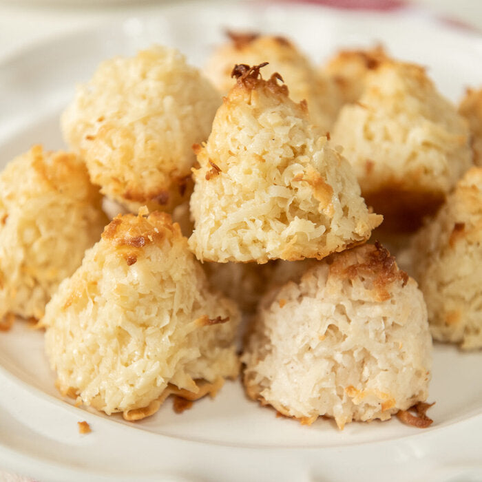 Close-up of vegan coconut macaroons with golden-browned tops and shredded coconut texture on a white plate