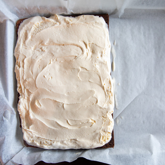 Top view of ice cream slab showing smooth vanilla ice cream spread over a chocolate Einkorn cookie base on parchment