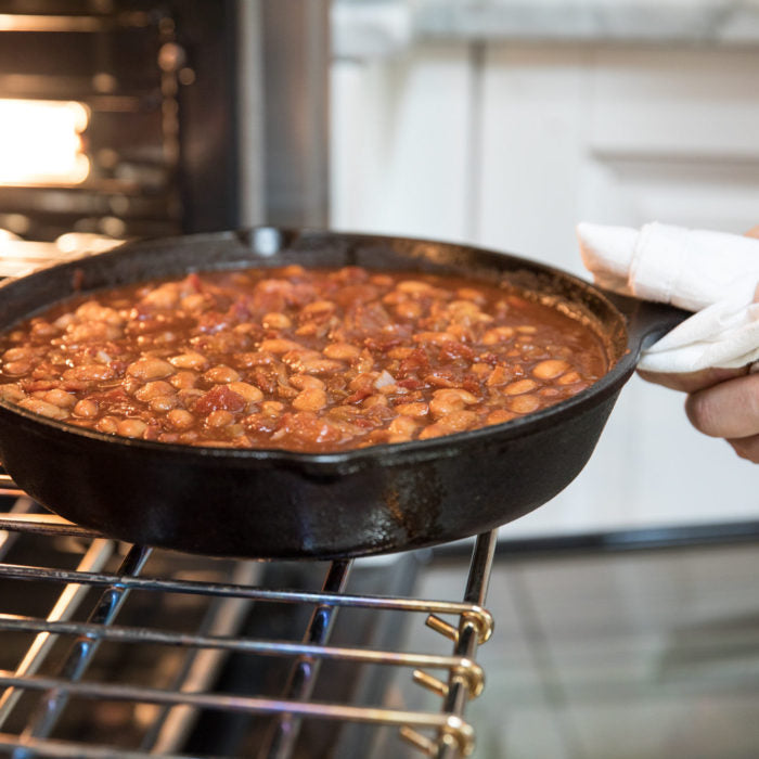 Baked borlotti beans in a cast-iron skillet being removed from an oven in a home kitchen