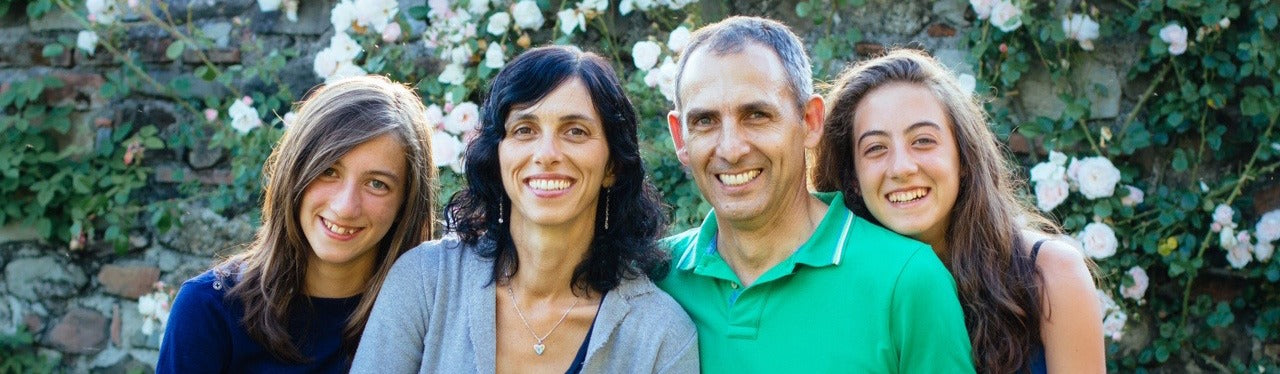 Bionaturae founders and their two teenage daughters smiling in front of a stone wall with climbing roses