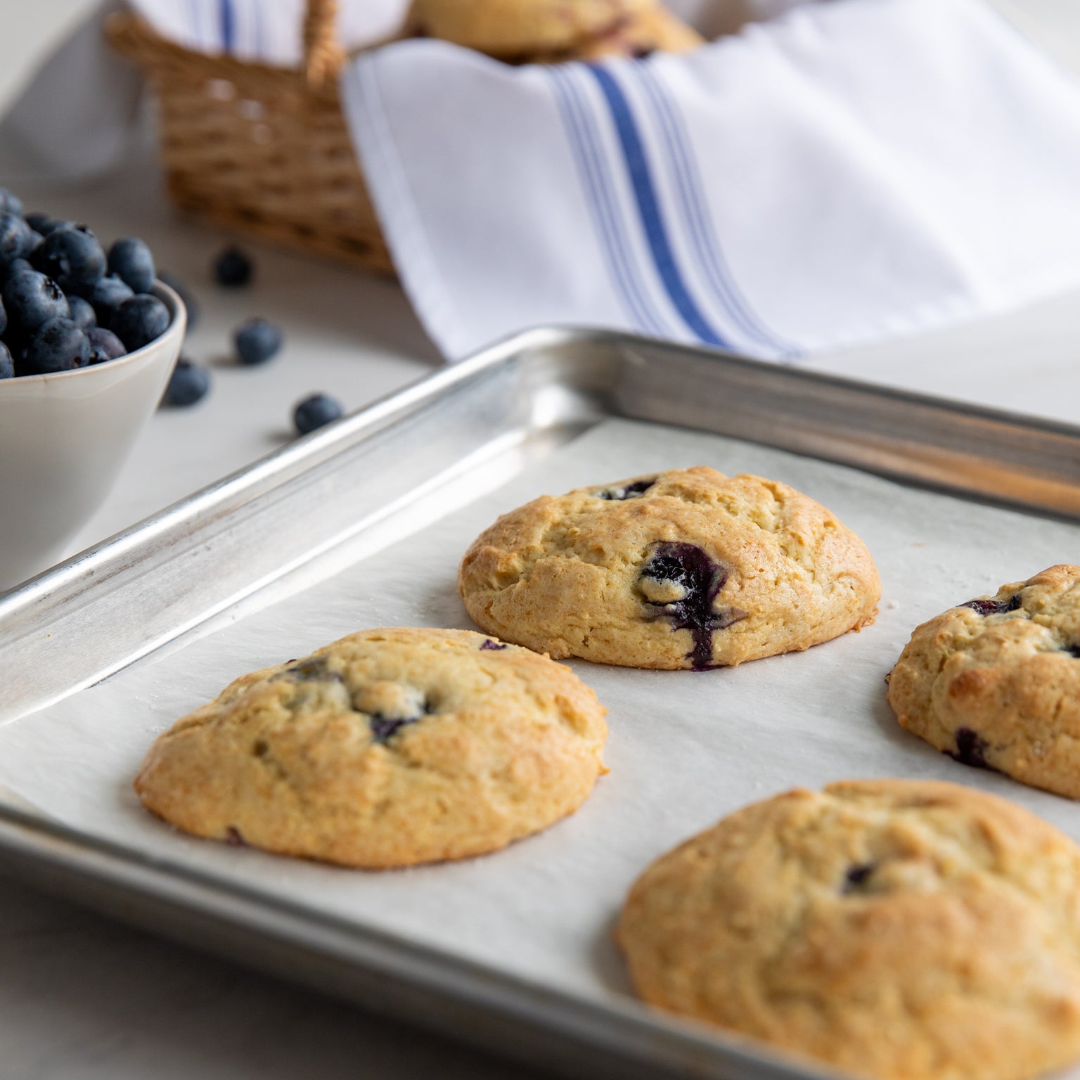 Close-up of Einkorn drop scones showing golden tops and juicy blueberries on a baking sheet