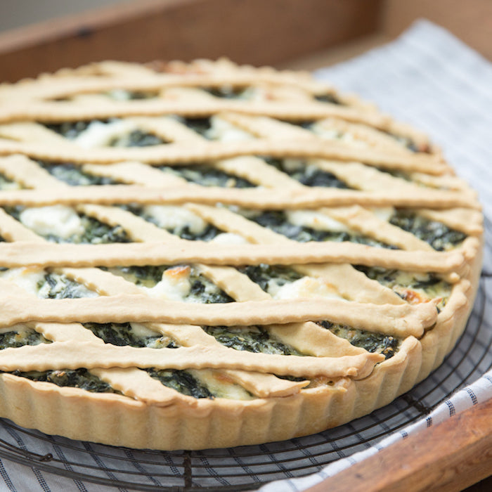 Close-up of a lattice-topped spinach and ricotta pie with golden einkorn crust on a cooling rack