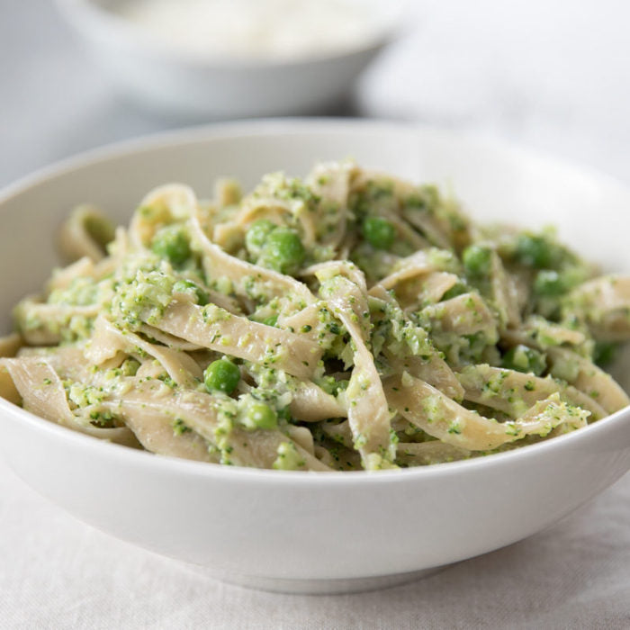 Creamy broccoli tagliatelle with peas served in a white bowl on a light cloth