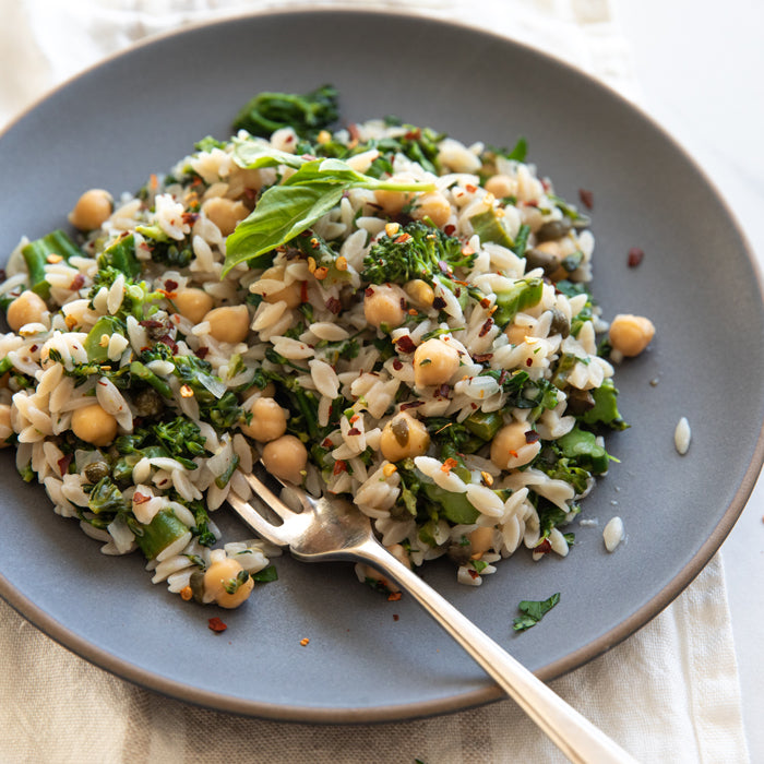 Broccolini orzo with chickpeas served on a gray plate with a fork