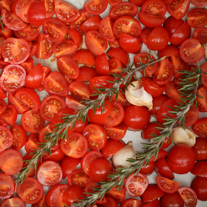 Organic cherry tomatoes halved and roasted with garlic and rosemary on a baking sheet
