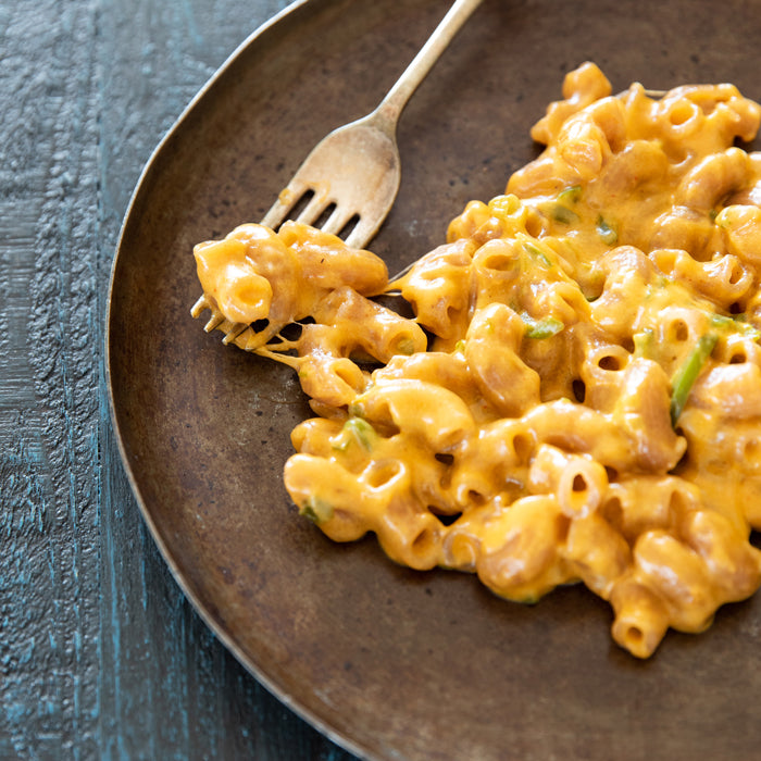 Forkful of creamy Mexican-style mac and cheese made with gluten-free cassava elbow pasta on a dark plate