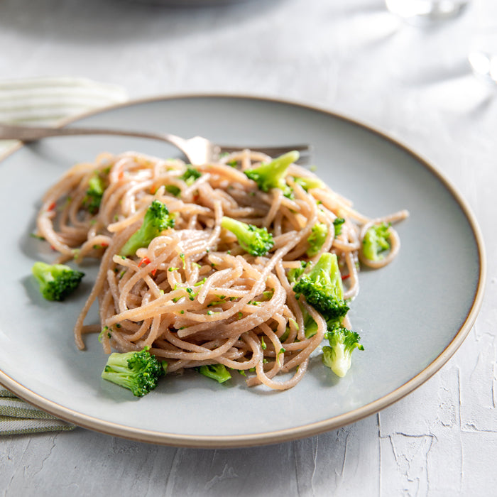 Gluten-free spaghetti tossed with broccoli and garlic-chili oil on a gray plate