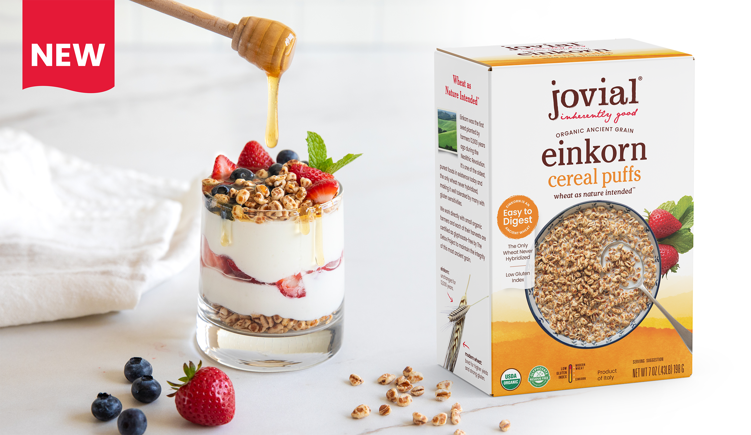Three-quarter view of Jovial Einkorn cereal puffs box with a yogurt and berry parfait topped with cereal puffs and honey drizzle, NEW banner