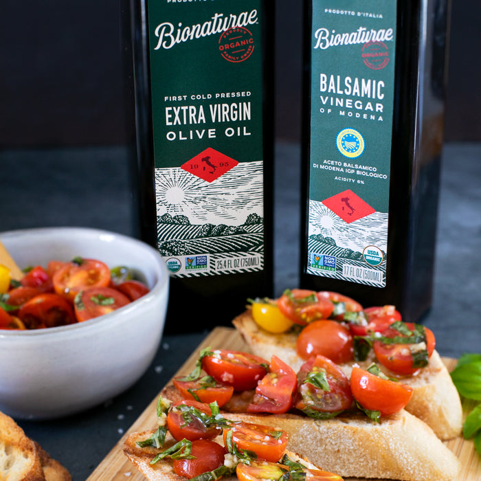 Cherry tomato bruschetta on sliced baguette with basil, with bottles of organic olive oil and balsamic in background