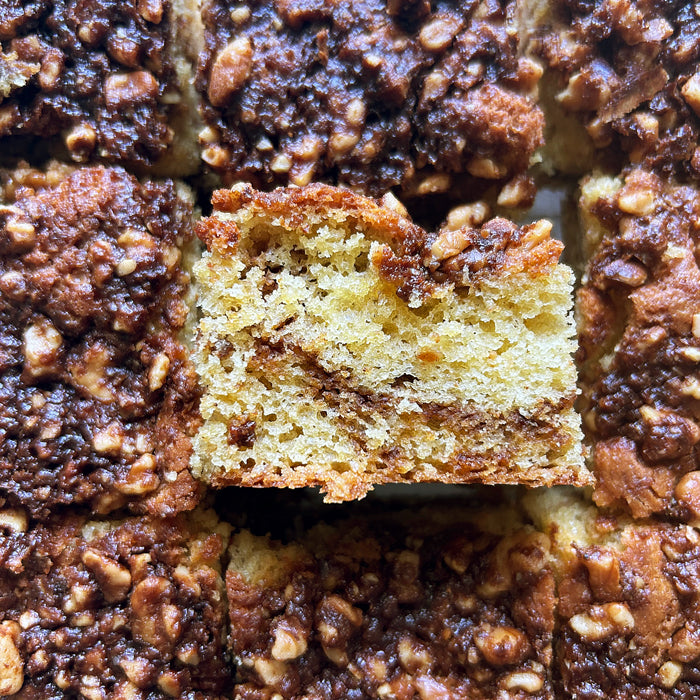 Top-down view of a sliced sourdough einkorn cinnamon coffee cake showing cinnamon swirl and walnut crumble topping