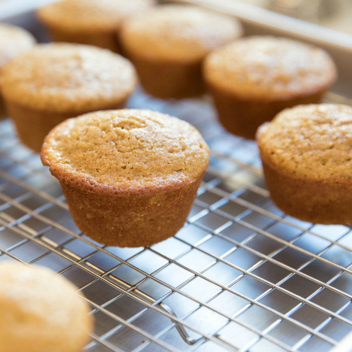 Close-up of einkorn corn muffins cooling on a wire rack showcasing golden-brown tops and tender crumb