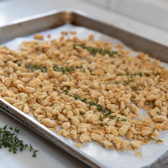 Overhead view of golden, crispy cannellini beans with thyme on a parchment-lined baking sheet