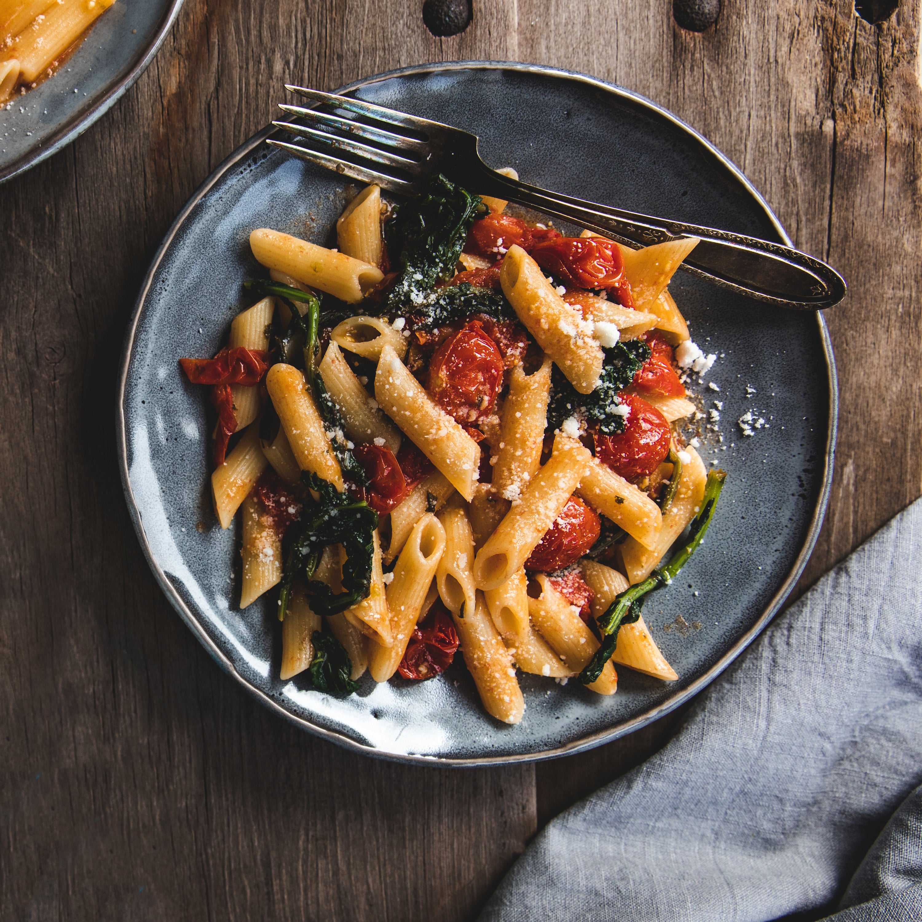 Penne rigate tossed with garlicky broccoli rabe in a rustic ceramic bowl on a wooden table