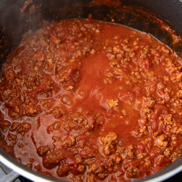 Simmering pot of chunky Bolognese sauce with ground meat and tomatoes on the stovetop