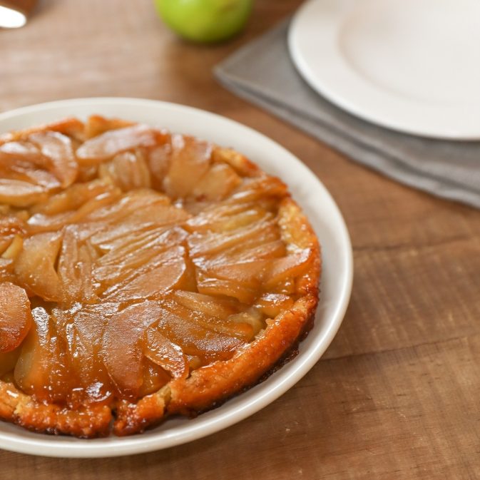 Top-down view of Einkorn tarte tatin showing caramelized apples and golden crust on a white plate