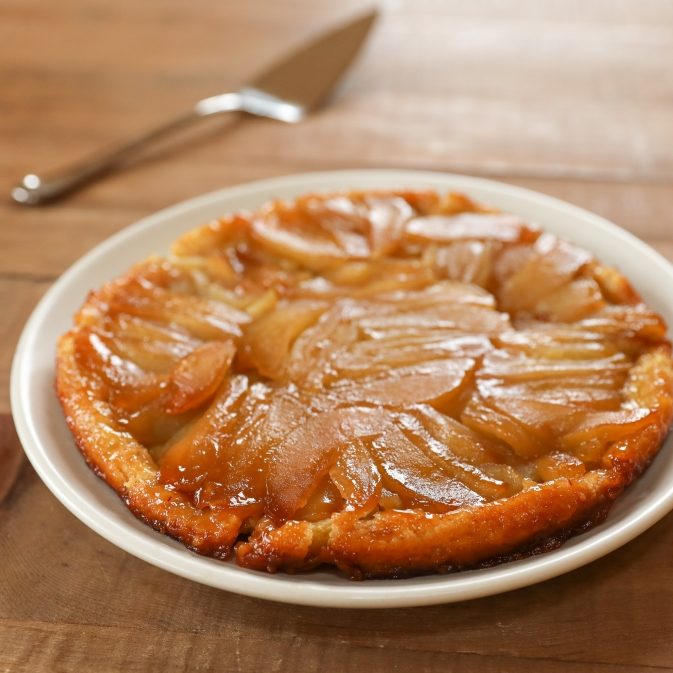 Overhead view of Einkorn tarte tatin with caramelized apple slices and golden crust on a white plate