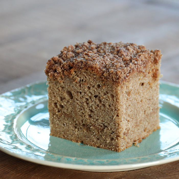 Front view of an Einkorn sour cream coffee cake slice with moist crumb and cinnamon streusel on a turquoise plate