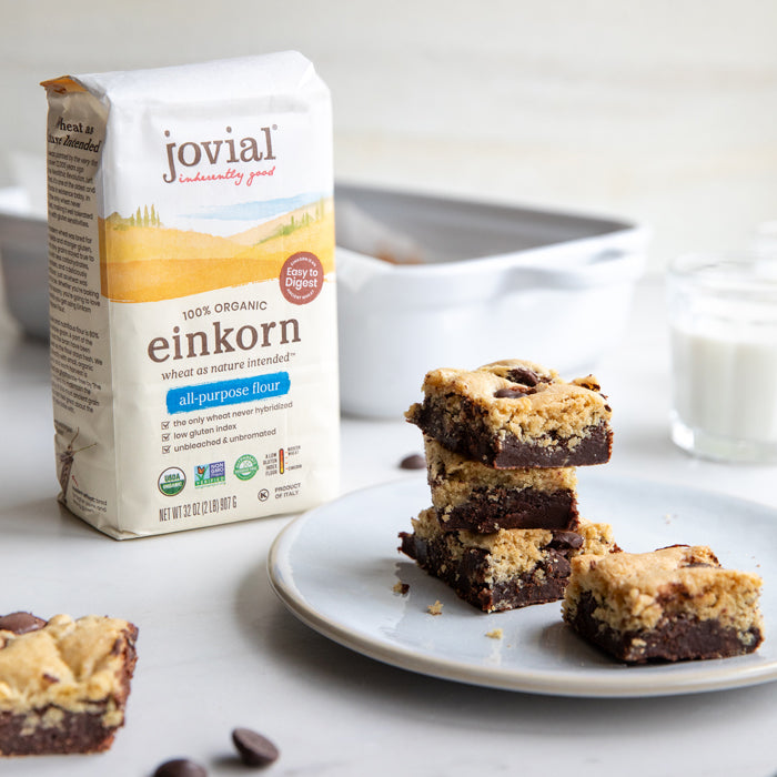 Stack of einkorn brookies on a plate beside a bag of Jovial organic einkorn all-purpose flour and a white baking dish
