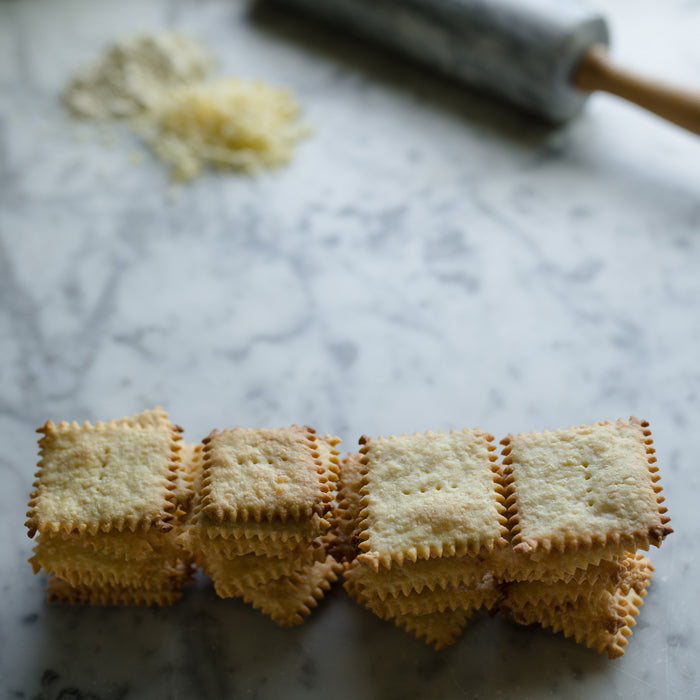 Close up of stacked Einkorn cheddar crackers showing golden edges and crispy texture on a marble countertop