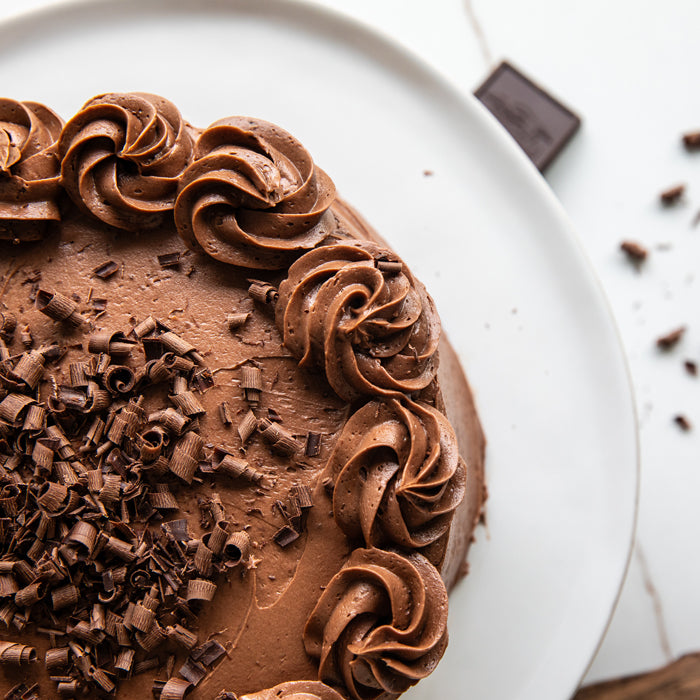 Top-down close-up of Einkorn chocolate cake showcasing chocolate buttercream rosettes and shaved chocolate on a white plate