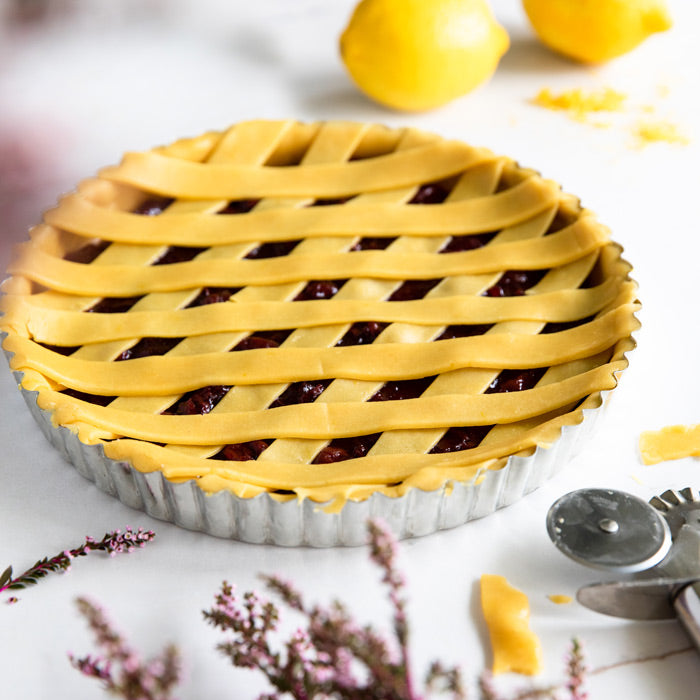 Sour cherry crostata with a golden lattice crust on a white plate, styled as a serving suggestion
