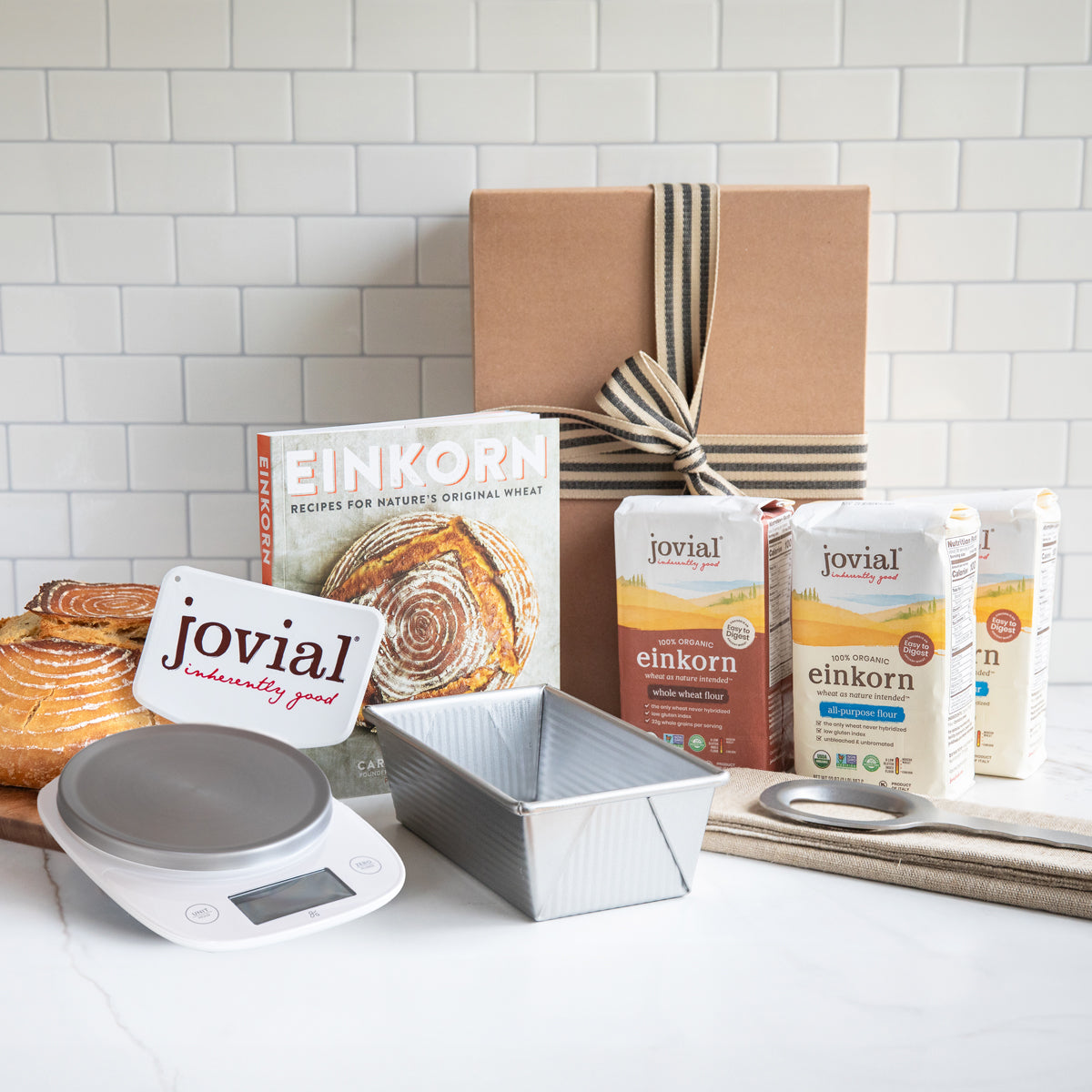 Angled view of Premium Einkorn Baking Kit with Jovial einkorn flours, loaf pan, digital scale, and ribboned gift box