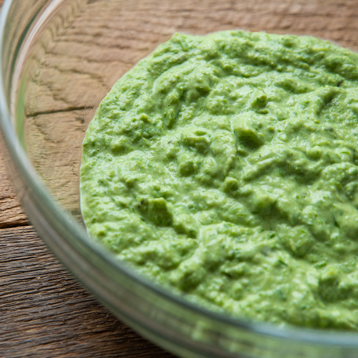 Bowl of creamy asparagus and ricotta sauce for pasta in a glass bowl on a wooden surface