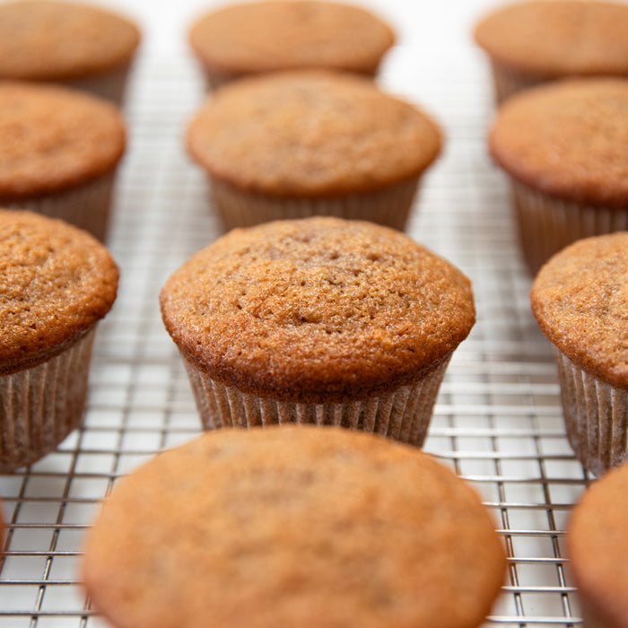Close up of Einkorn strawberry cupcakes showcasing golden brown tops and paper liners on a wire cooling rack