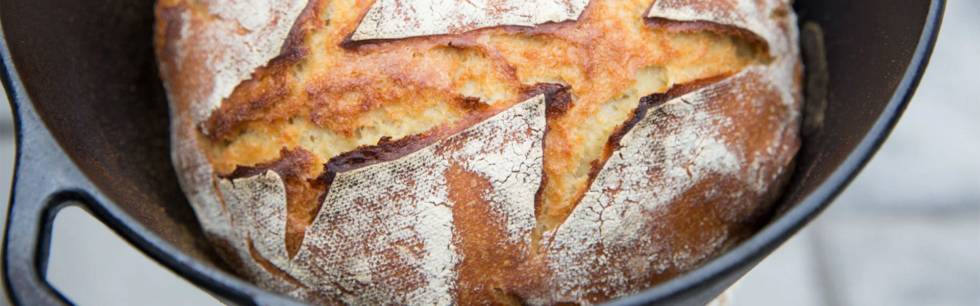 Rustic sourdough loaf with scored crust baked in a cast-iron Dutch oven