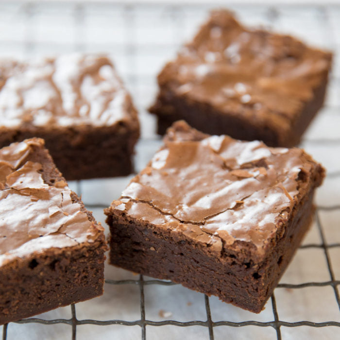 Close-up of four fudgy Einkorn mocha brownie squares with cracked glossy tops and dense chocolate centers on a cooling rack