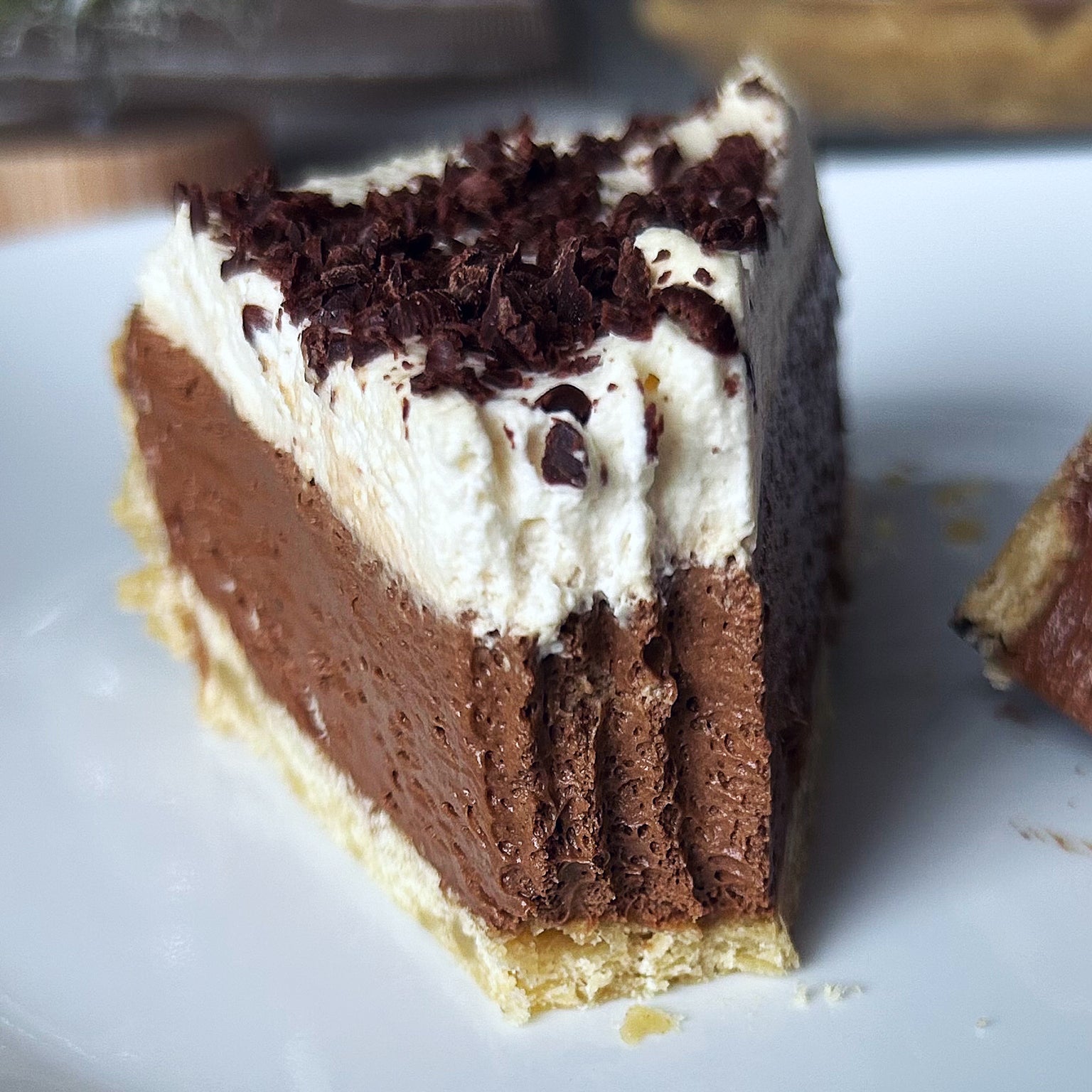 Close up of a slice of sourdough French silk pie with chocolate mousse, whipped cream, chocolate shavings on einkorn crust