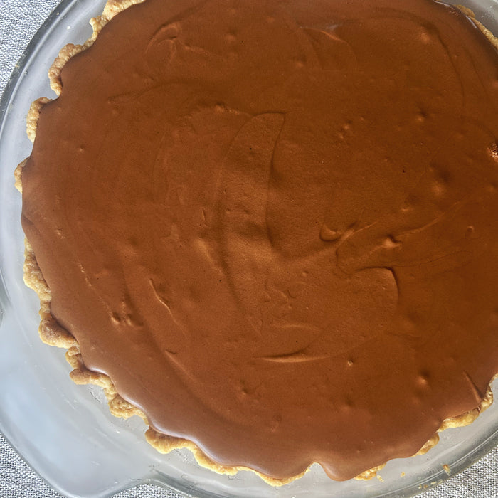 Top-down view of French silk pie with smooth chocolate mousse and fluted sourdough crust in a glass pie dish