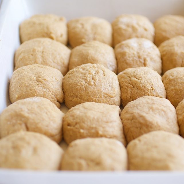 Close-up of 20 Einkorn whole-grain dinner rolls in a white baking dish, showing their soft, rustic texture