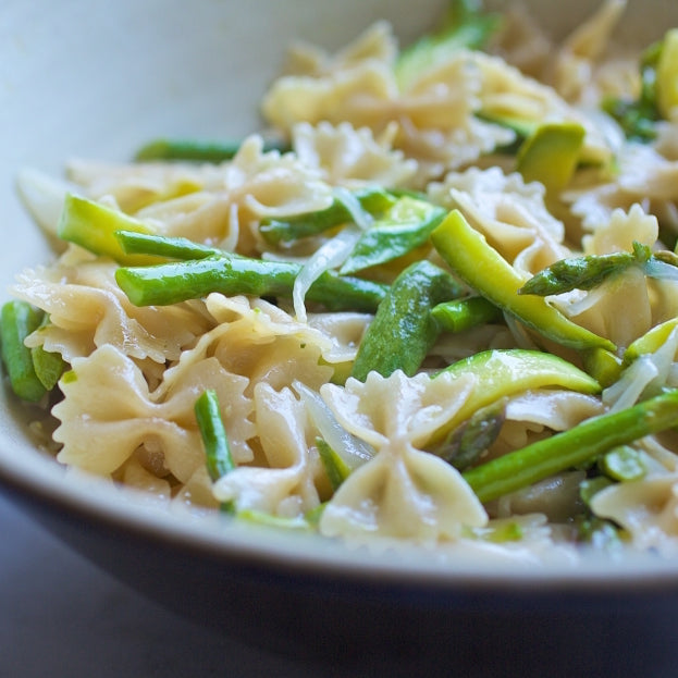 Close-up of gluten-free farfalle with asparagus and zucchini showcasing bow-tie pasta and bright green vegetables in a light sauce