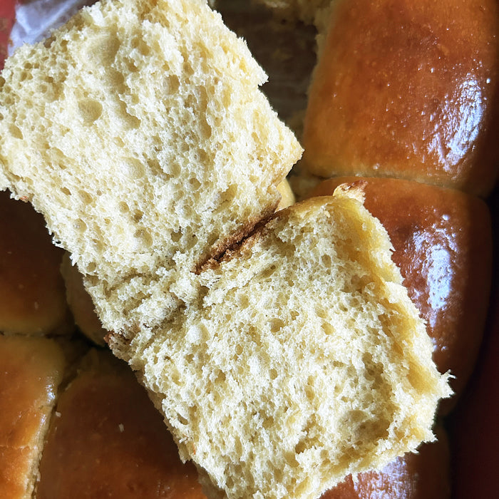 Close-up of pulled-apart sourdough Hawaiian rolls made with einkorn, showing fluffy airy crumb and glossy golden-brown tops
