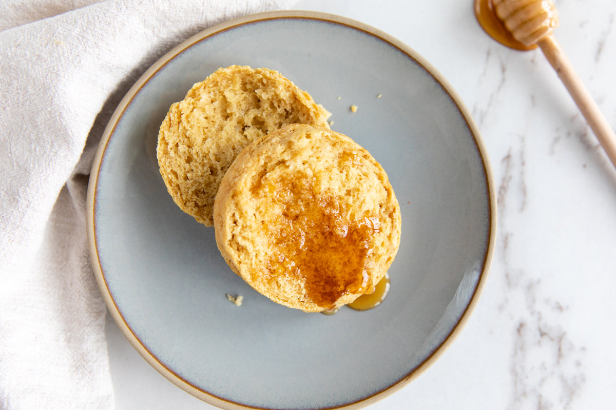 Overhead view of an open Einkorn honey biscuit with honey drizzle and crumbly texture on a gray plate
