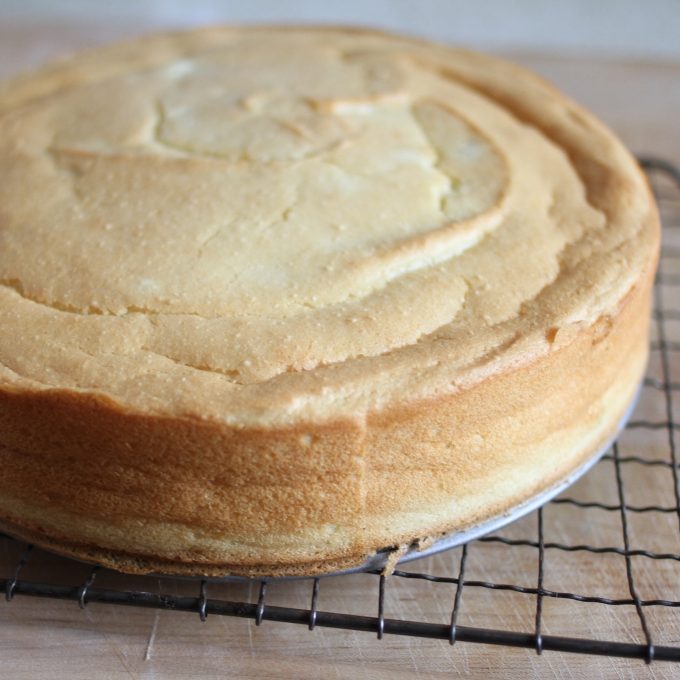 Three-quarter view of gluten-free sweet potato sponge cake with light airy crumb and golden sides on a wire cooling rack