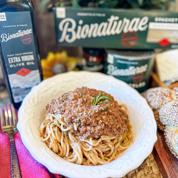 Bowl of spaghetti with meatless mushroom bolognese, on a table with a Bionaturae pasta box and olive oil bottle in the background