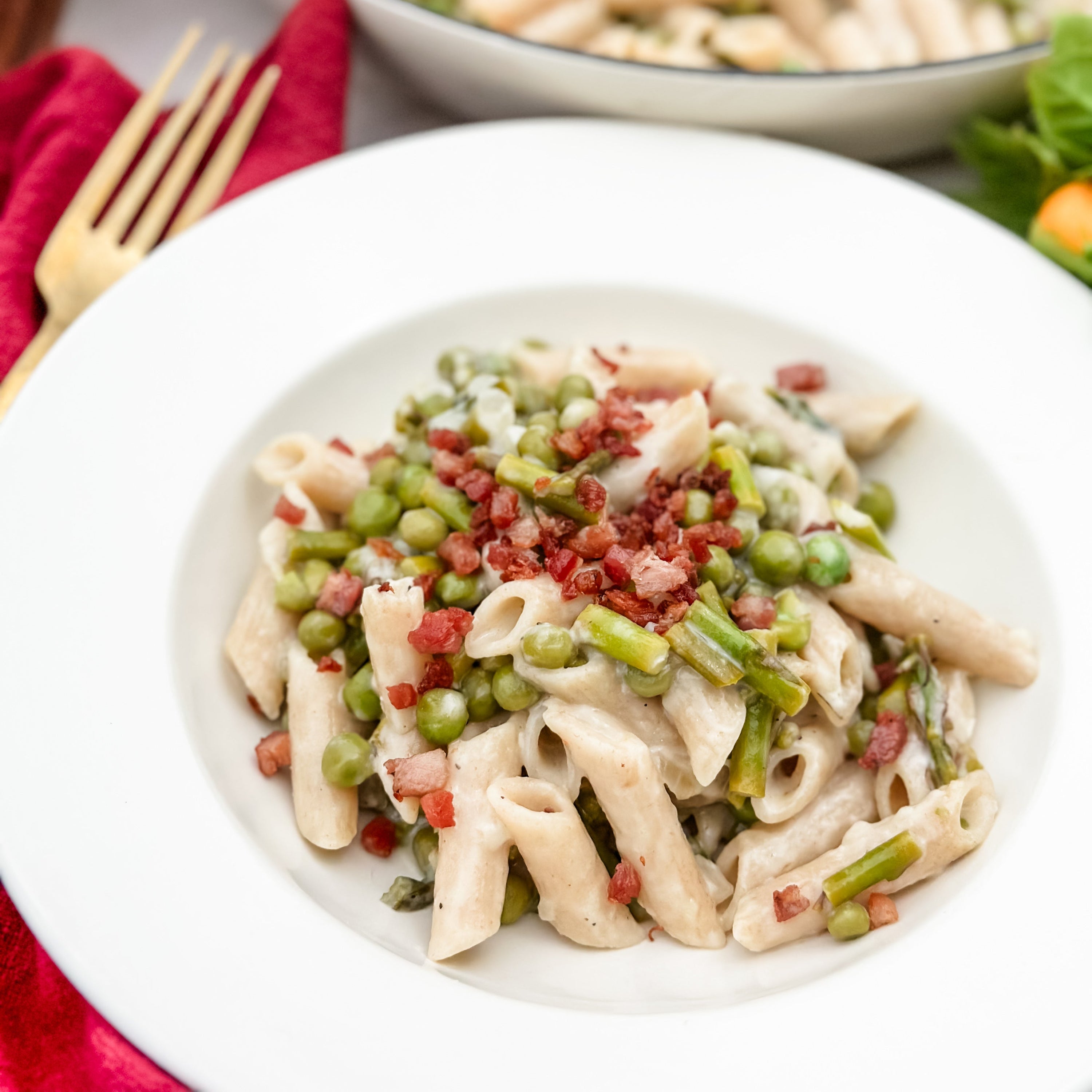 Penne rigate made from organic durum semolina, tossed with peas and a crumbled garnish, served on a white plate