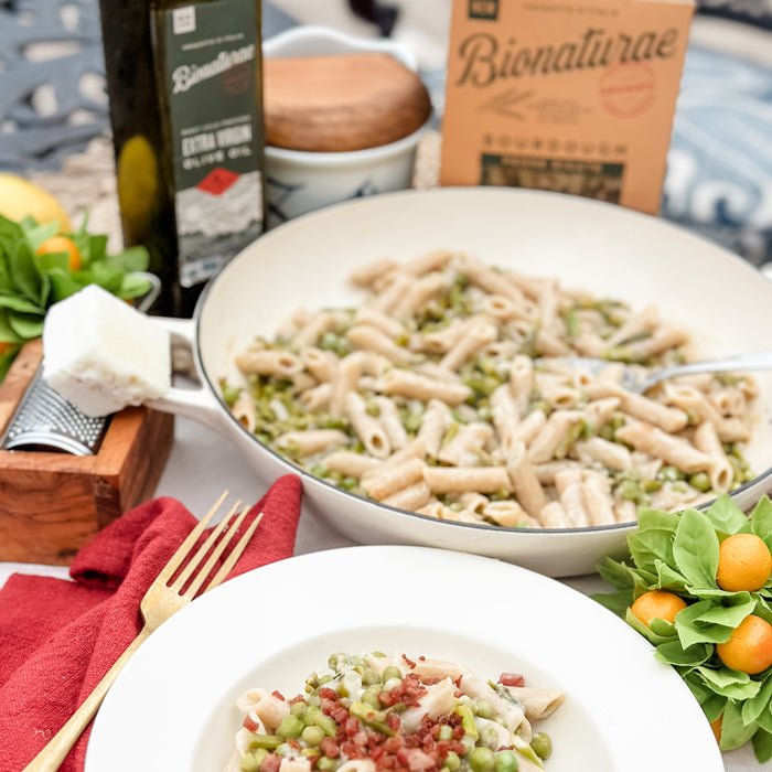 Sourdough penne with asparagus and peas plated with grated cheese, pan of pasta and Bionaturae box in background