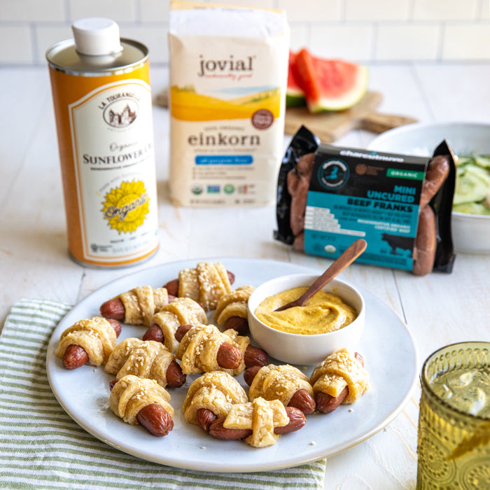 Plate of mini pigs in a blanket with mustard, golden Einkorn pastry, Jovial flour and Charcutnuvo franks in background